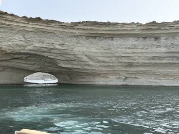 A stunning view of a natural rock arch along the coastline, showcasing the beauty of the surrounding waters — perfect for scenic boat tours.