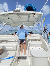A man stands inside the helm of a boat, showcasing the spacious interior and seating arrangements — perfect for navigating the open waters.