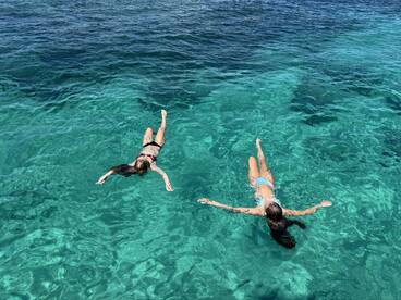 Two friends enjoy a refreshing swim in crystal-clear waters, showcasing the perfect summer getaway experience.