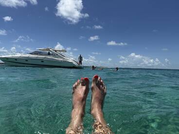 A relaxing day on the water with friends, featuring a boat in the background and people enjoying the clear, turquoise waters.