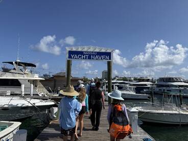 A group of guests walks along the dock at Nassau Yacht Haven, surrounded by luxury yachts — a perfect start to a day of boating adventures in the Bahamas.