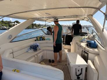 Inside view of a boat's cabin featuring guests interacting and enjoying the space, showcasing comfortable seating and a helm area.