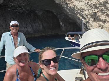 A cheerful group enjoys a boat trip near a stunning cave, capturing a memorable moment together — perfect for adventure seekers and nature lovers.