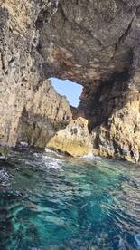 A stunning view of a natural rock arch over crystal-clear waters, showcasing the beauty of coastal landscapes — perfect for exploring hidden gems during boat trips.