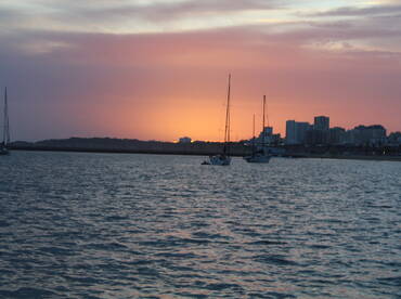 A serene sunset view featuring sailboats anchored in the harbor, creating a picturesque scene perfect for evening relaxation on the water.