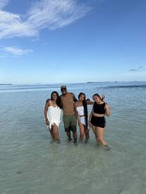 A cheerful group enjoys a day at the beach, wading in shallow waters under a clear blue sky — perfect for memorable summer outings.