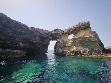 A stunning view of a natural rock formation arching over crystal-clear waters, perfect for showcasing the beauty of coastal landscapes.