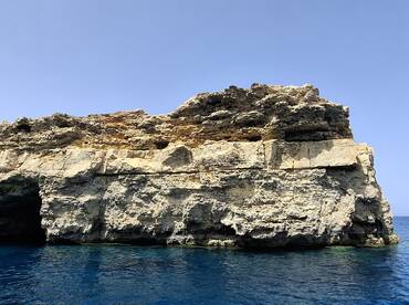 A stunning view of a rocky coastline against the clear blue waters, perfect for showcasing the natural beauty of the area.