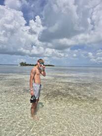 A young boy enjoys a sunny day in shallow, clear waters, ready for snorkeling adventures — a perfect beach day experience.