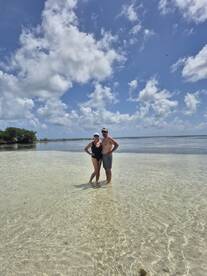 A couple enjoys a sunny day standing in the clear waters of a beautiful beach, perfect for romantic getaways and tropical adventures.