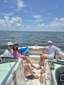 A group of friends relaxes on a boat under a sunny sky, enjoying their time on the water — perfect for summer outings and adventures.