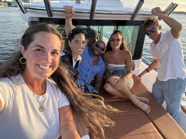 A lively group of friends enjoys a fun moment aboard a boat, capturing memories against a beautiful waterfront backdrop.