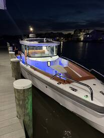 A sleek boat docked at night, illuminated by ambient lighting, showcasing its stylish design and inviting atmosphere.