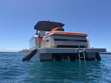 A sleek yacht named 'Chic & Tonic' is docked, showcasing its stylish design against a clear blue sky and tranquil waters.