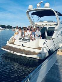 A lively group of friends celebrates aboard a yacht named 'No Regrets' in West Palm Beach, capturing the essence of fun and friendship on the water.