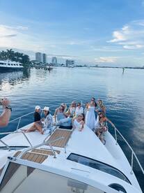 A lively group of friends enjoys a fun day on a yacht, capturing memories against a stunning waterfront backdrop — perfect for celebrations and gatherings.