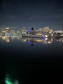 A stunning yacht docked at night, reflecting the vibrant city skyline in the calm waters — perfect for luxury charters and evening cruises.