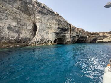 A stunning view of rocky cliffs and a cave along a vibrant blue coastline, perfect for exploring the natural beauty of the area.