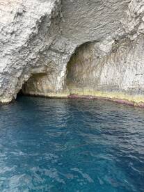 A stunning view of a rocky cave along the coastline, showcasing the vibrant blue waters — a perfect spot for exploration and adventure.