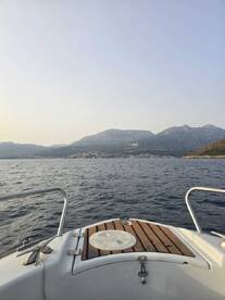 A serene view from the front of a boat, showcasing the calm waters and distant mountains, perfect for a peaceful day on the water.