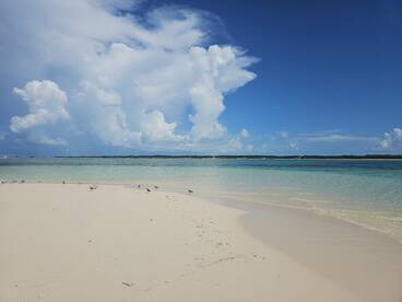 A scenic view of a beach with clouds and clear waters, capturing the serene beauty of a tropical destination.