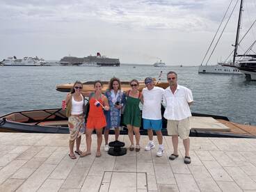 A cheerful group of friends poses together on the dock next to a stylish boat, capturing a memorable moment before their adventure on the water.