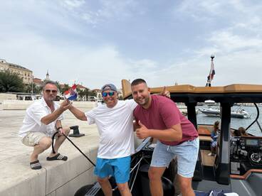 A cheerful group of friends celebrates by a boat in a vibrant marina, showcasing the joy of boating adventures together.
