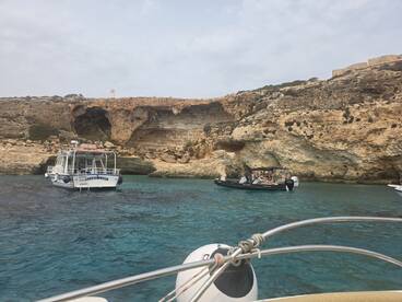 A scenic view of two boats navigating through crystal-clear waters near a rocky coastline, showcasing the beauty of the landscape and the joy of boating adventures.
