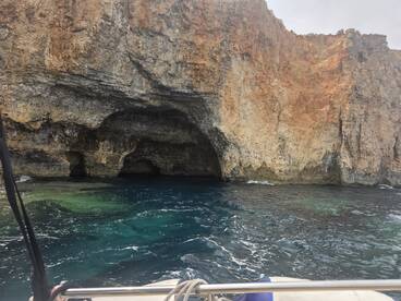 A stunning view of a rocky coastline with a cave entrance, showcasing the natural beauty of the ocean — perfect for exploring scenic destinations by boat.