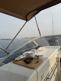 A beautifully arranged outdoor cooking setup on a boat featuring grilled steaks and utensils, perfect for a delightful dining experience on the water.