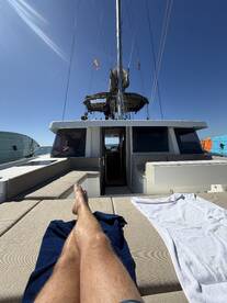 A relaxing moment on the lounge area of a catamaran, showcasing comfortable seating under a clear blue sky — perfect for sunbathing and enjoying the sea breeze.