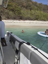 Guests enjoy a relaxing day at the beach, swimming in clear waters near a pontoon boat — perfect for summer outings and fun in the sun.