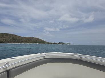 A scenic view from the bow of a boat, showcasing a beautiful coastline and lush island landscape — perfect for exploring tropical destinations.