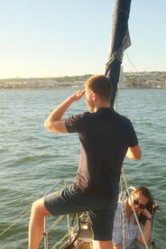 A man salutes while sailing, enjoying a beautiful day on the water with a companion — perfect for capturing memorable moments on a boat trip.