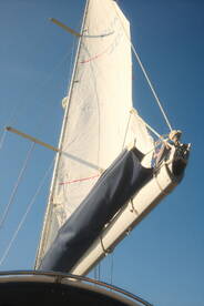 A close-up view of a sailboat's sail against a clear blue sky, showcasing the vessel's elegant design and readiness for sailing.