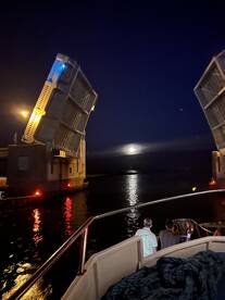 Guests enjoy a scenic night view as a bridge opens under the moonlight, creating a picturesque backdrop for a memorable boating experience.