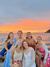 A joyful group of friends poses together on a boat at sunset, capturing a perfect moment of celebration and camaraderie on the water.
