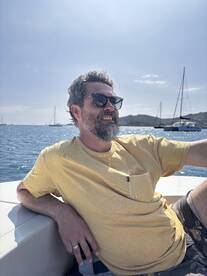 A man relaxes on the deck of a boat, enjoying the ocean view and sunshine — a perfect moment for leisure on the water.