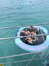 A joyful group of family members enjoys a fun day in a floating mat, surrounded by clear turquoise waters — perfect for family bonding and summer adventures.