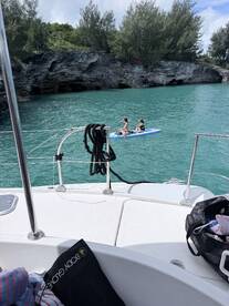 Two friends enjoy paddleboarding in crystal-clear waters, surrounded by stunning rocky cliffs — a perfect day for adventure and relaxation on the water.