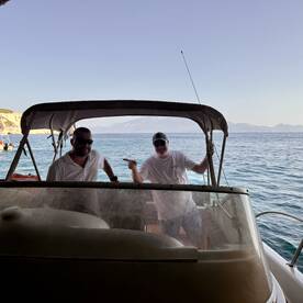 Two men enjoy a fun moment aboard a boat, showcasing the joy of boating adventures in a picturesque setting.