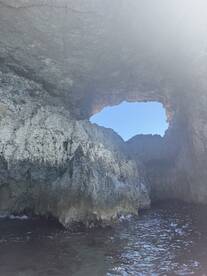 A stunning view of a natural rock formation with a cave opening, showcasing the beauty of coastal scenery — perfect for exploring hidden gems by boat.