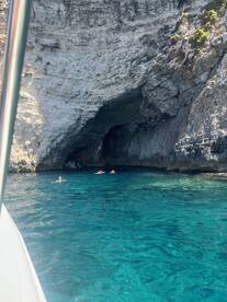 Swimmers enjoy the stunning clear waters near a cave, showcasing the beauty of the coastline and perfect for adventure seekers.