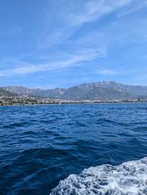 A stunning view of the coastline and mountains from the water, showcasing the beautiful landscape perfect for a day of exploration.
