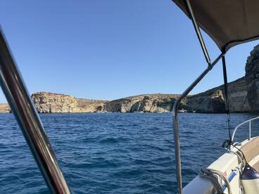 A scenic view of a coastline from a boat, showcasing stunning cliffs and clear waters — perfect for exploring beautiful destinations.