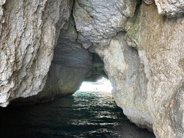 A stunning view of a cave entrance with sunlight streaming through, showcasing the beauty of water exploration and adventure.