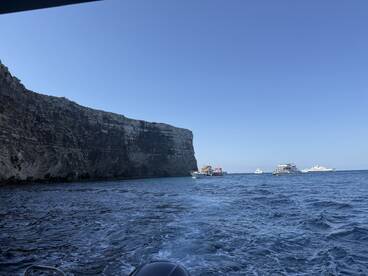 A scenic view of a rugged coastline with several boats anchored in the ocean, showcasing the beauty of a popular boating destination.