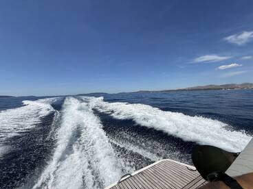 A stunning view from the back of a boat, showcasing the wake as it cuts through the clear blue waters, perfect for capturing the essence of a day on the sea.