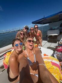 A lively group of friends enjoys a fun day on a pontoon boat, capturing memories with smiles and laughter under the sun.