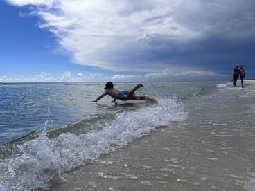 A child joyfully swims in shallow waters at the beach, capturing the essence of family fun and adventure in a picturesque coastal setting.